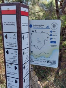 A close up of a recycled plastic pole with directional signs and a Poros cycling trails trailhead