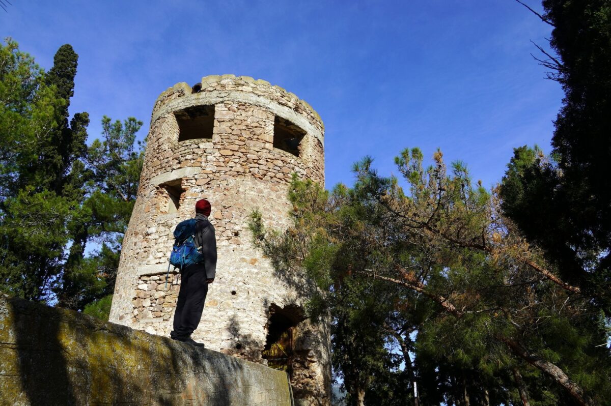 A hiker looking at an old wind mill over the city of Poros