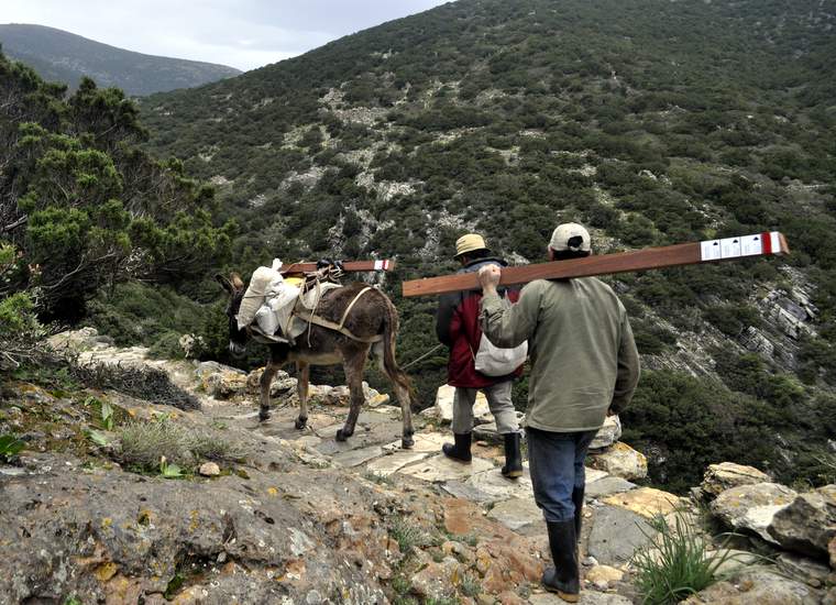 Locals and a donkey helping to transport trail signs on the island of Sifnos