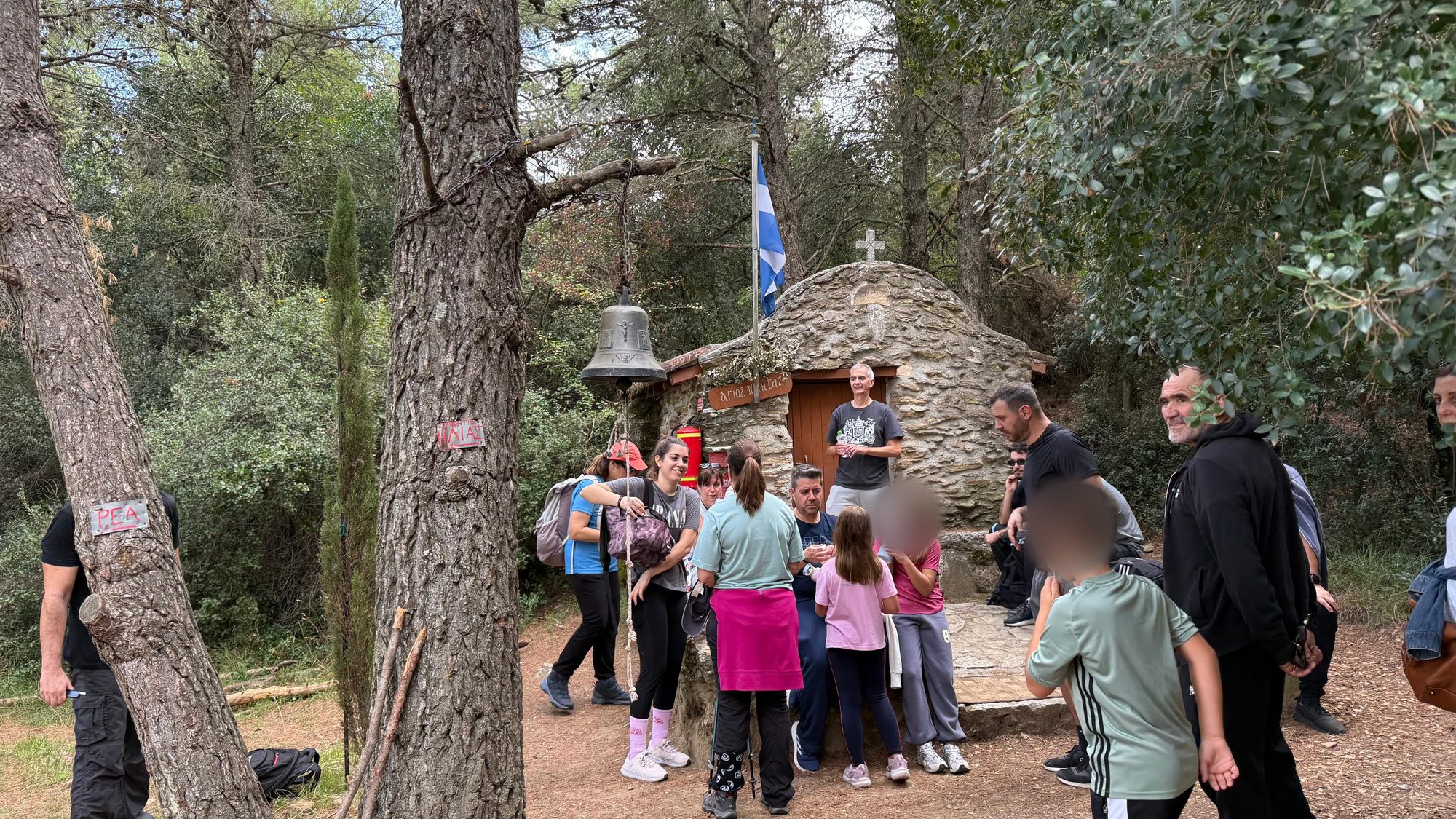 Hikers resting by the stone chapel of Agios Nikitas on trail D1 on Mount Penteli